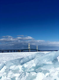 Snow covered landscape against blue sky