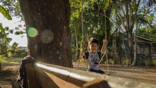 Portrait of boy sitting on swing in playground