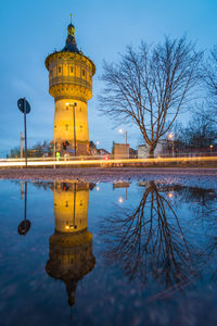 Reflection of illuminated building in lake against sky