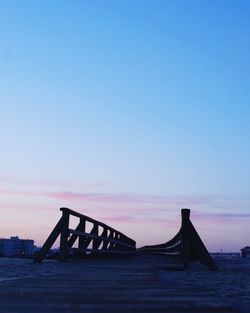 Silhouette built structure on beach against clear sky