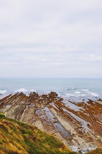 High angle view of rocky sea shore against cloudy sky