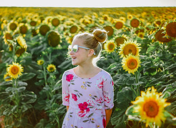Young woman standing amidst sunflowers