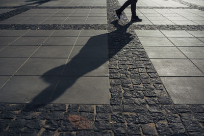 Low section of woman walking on cobblestone street