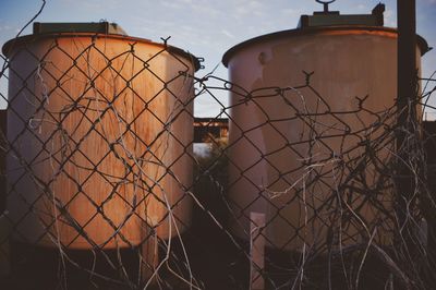 Broken chainlink fence against metallic containers at industry