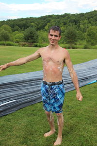 Young man standing against water slide on field