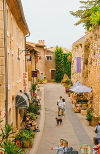 People on street amidst buildings in city against sky