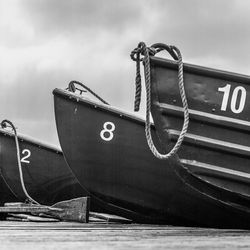 Close-up of boat moored at harbor against sky