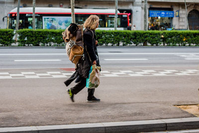 Full length of woman walking on road in city