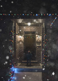 Boy in warm clothing standing at entrance during night