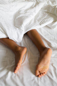 Low section of woman lying on bed