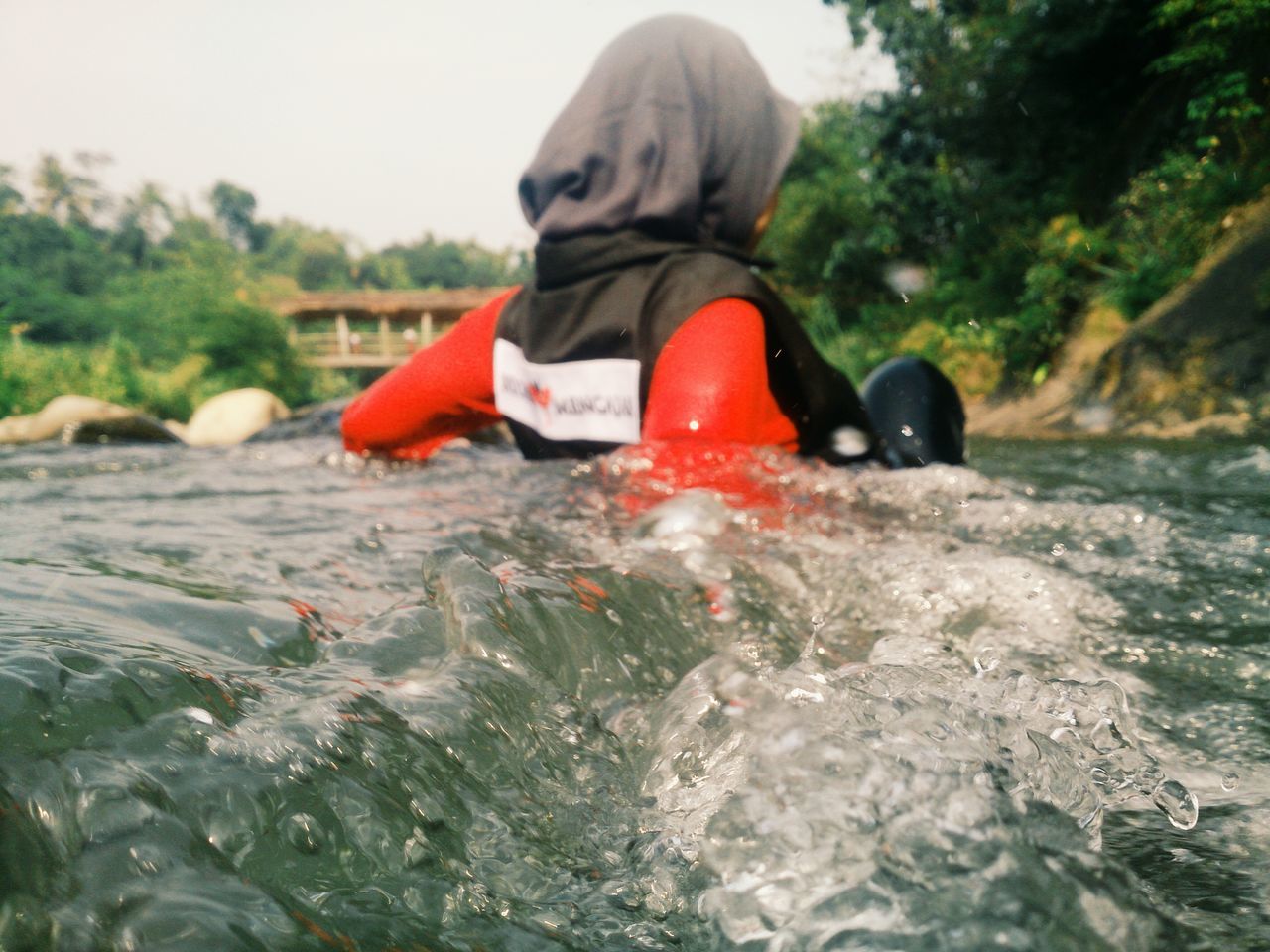 water, leisure activity, lifestyles, red, waterfront, tree, full length, motion, river, side view, nature, day, rear view, outdoors, men, lake, focus on foreground, rippled