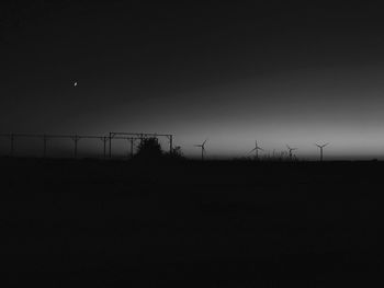 Silhouette of wind turbines on landscape against sky