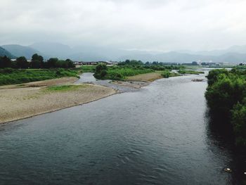 Scenic view of river against cloudy sky