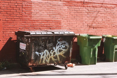 Garbage bin against brick wall