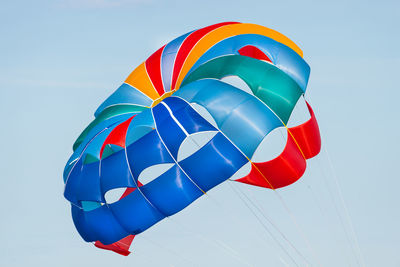 Close up shot of a colorful parachute used for parasailing pulled by a motorboat.