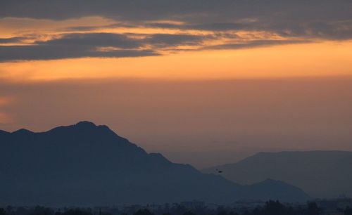 Scenic view of silhouette mountains against orange sky