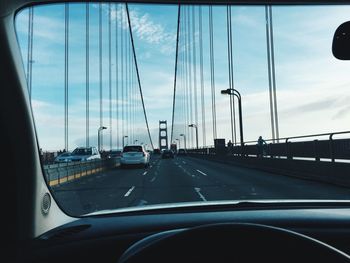 Cars on road against sky seen through car windshield