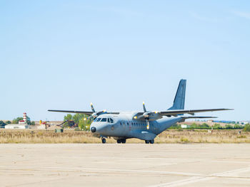 Airplane flying over airport runway against clear blue sky