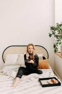 Portrait of smiling woman sitting on bed at home