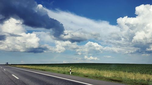 Road amidst field against sky