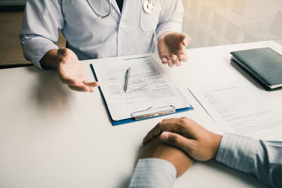 Midsection of doctor explaining patient on table