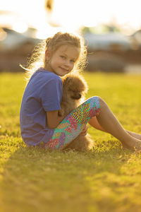 Portrait of girl sitting on field with dog