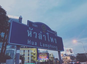 Low angle view of information sign in city against sky