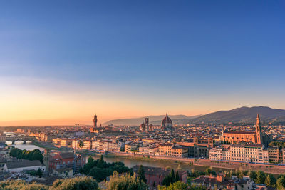 Aerial view of city buildings against mountain during sunset