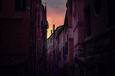 Narrow alley amidst buildings in city at night