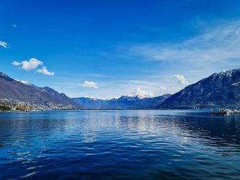 Scenic view of sea and mountains against blue sky