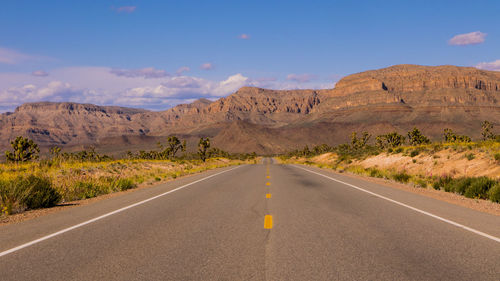 Road leading towards mountains against sky