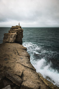 Rock formation on sea shore against sky