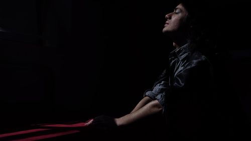 Side view of young man sitting in darkroom