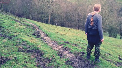 Rear view of man standing on meadow at forest