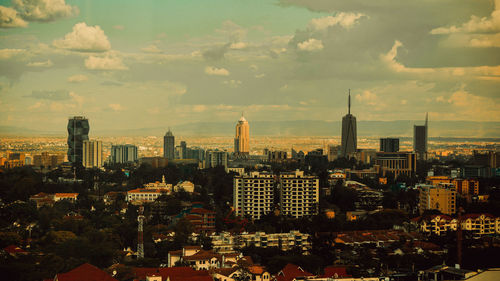 Aerial view of city buildings against cloudy sky