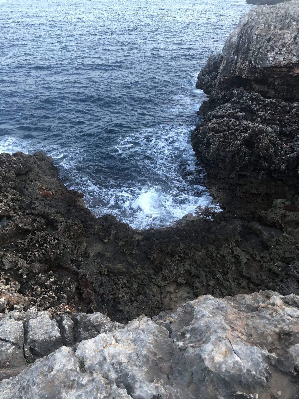 HIGH ANGLE VIEW OF ROCK FORMATION AT SEA