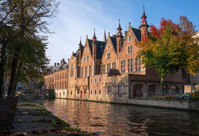 Arch bridge over river amidst buildings against sky