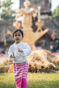 Portrait of girl holding stick while standing at public park