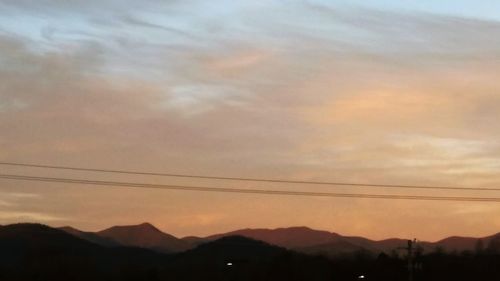 Scenic view of mountains against cloudy sky at sunset