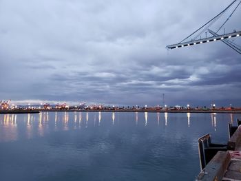 Scenic view of river by cityscape against sky