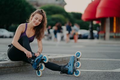 Young woman sitting on street in city