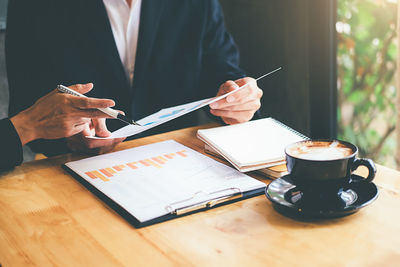 Midsection of man working with coffee cup on table