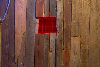 Close-up of red flag hanging on wooden door of building