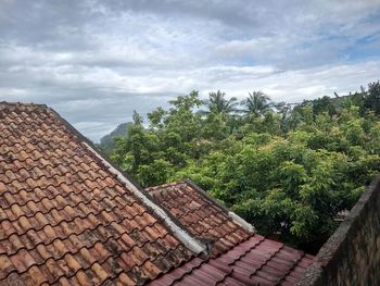 Stone roof of house and trees against sky