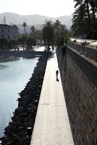 Man walking on retaining wall by sea against clear sky