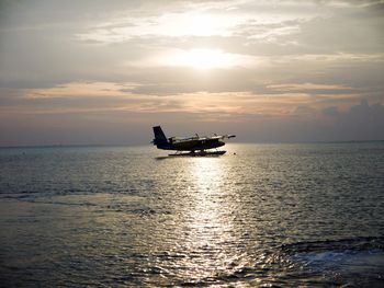 Boats in sea at sunset