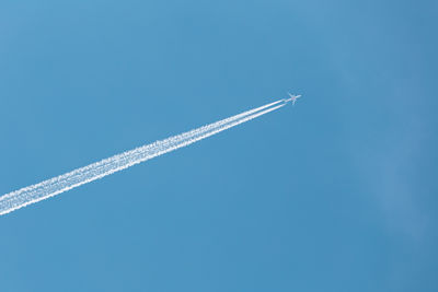 Low angle view of airplane flying against clear blue sky