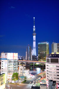 Illuminated buildings in city against blue sky