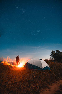 Man standing in tent against sky at night