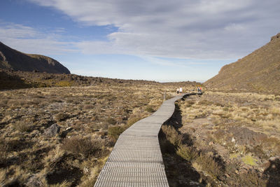 People on walking trail across volcanic landscape at tongariro trek